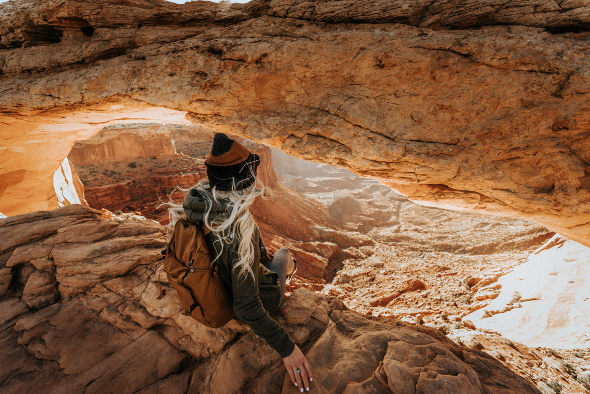 Girl Sitting on Edge at Mesa Arch Moab Utah Hiking Trail